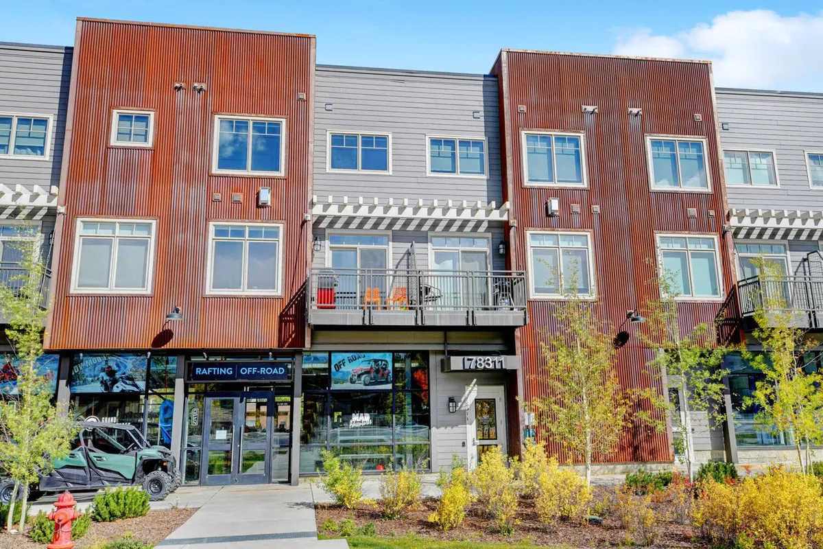 A vibrant exterior view of a storefront with balconies and lively landscaping, where people are enjoying meals outdoors and exploring local shops. The scene is energetic and community-focused.