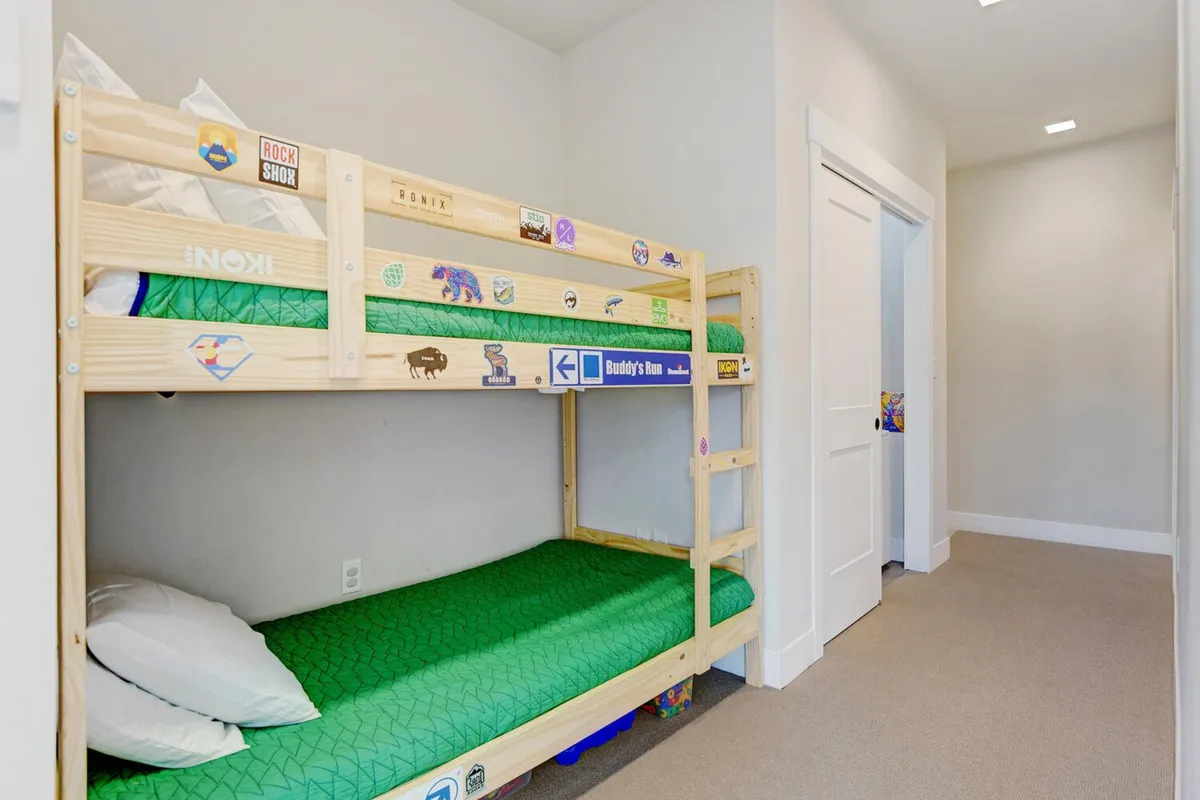 A cozy bunk bed nook with green bedding, whimsical wall stickers, and a playful, inviting atmosphere. The space feels like an imaginative hideaway, perfect for children or young-at-heart guests to curl up for bedtime stories or afternoon naps.