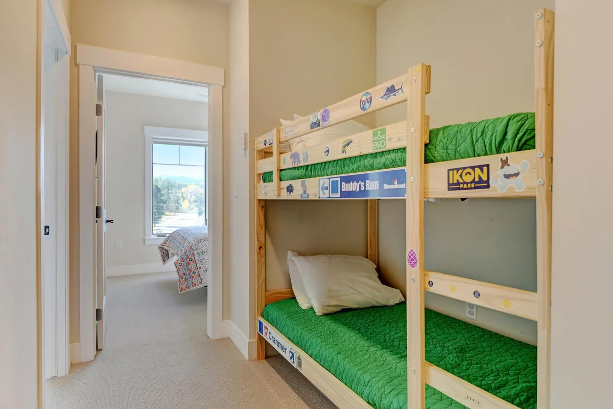 A playful, relaxing bedroom with bunk beds dressed in green bedding and decorated with whimsical stickers. The room evokes feelings of togetherness and childhood fun, ideal for families or groups traveling together.