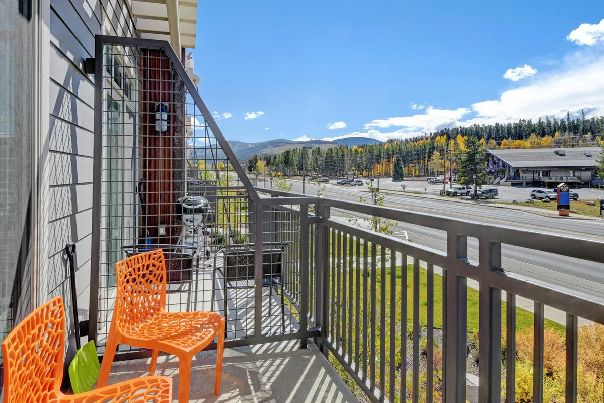An outdoor seating area with bright orange chairs overlooks a panoramic mountain view. The setting is cheerful and inviting, offering a sense of relaxation and connection to the mountain environment—ideal for après-ski unwinding or socializing.