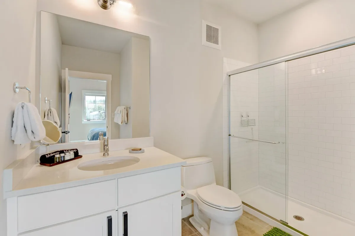 A modern bathroom with a large glass shower enclosure, marble vanity with sink, fresh towels, and a spacious mirror. The setting is bright, clean, and inviting—evoking a sense of spa-like comfort and indulgence.